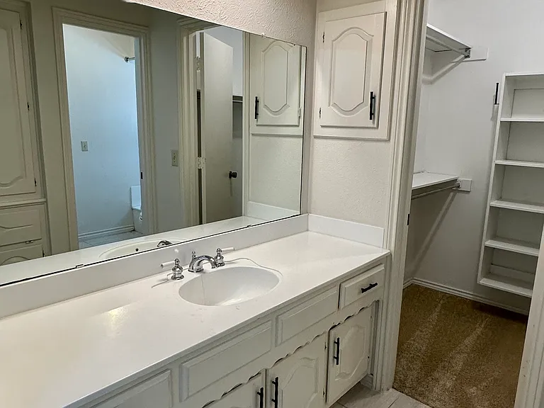 His and Hers primary bathroom with vanity, tile floors and each with their own closet