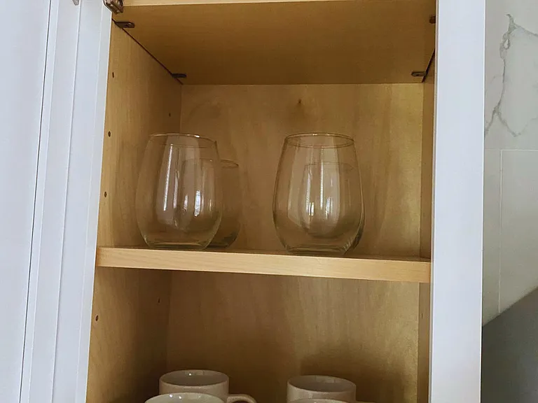 One kitchen cabinet includes glass cups and coffee mugs.