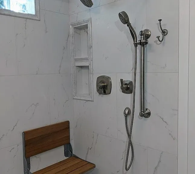 Shower with seat, grab bar and hand shower option.
