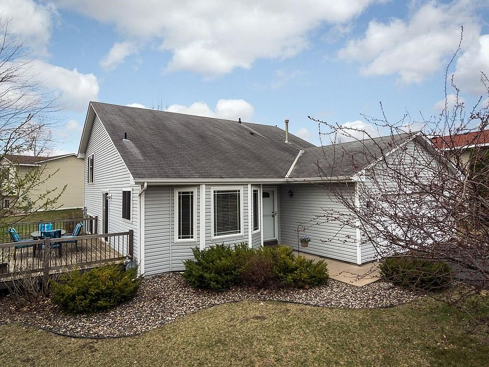 Attractive 3-Level Split has no-maintenance vinyl siding with prairie style grills in front bay window and gutters all in neutral gray/white exterior color scheme.