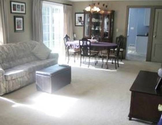 The open living and dining room areas with a view of the newer glass sliders to the side deck with newer baseboards and trim.