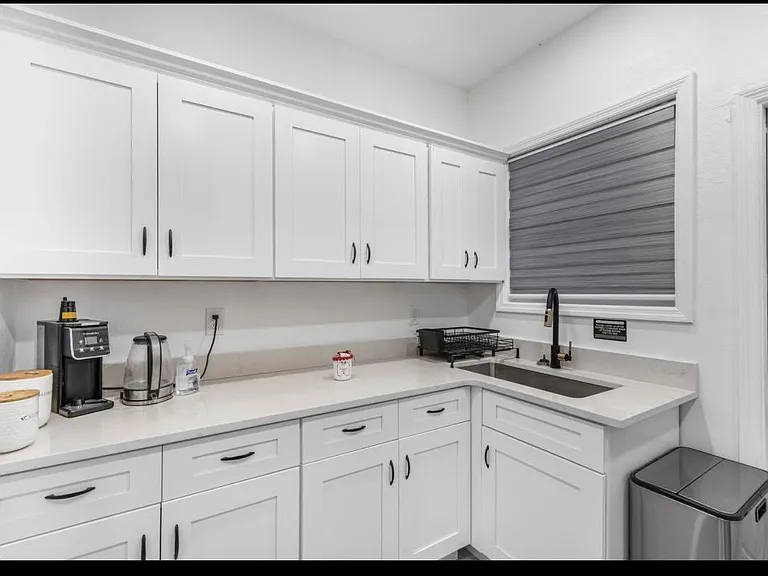 Kitchen prep area with ample shaker cabinets, long counters, and an undermount sink beneath a window for easy cleanup.