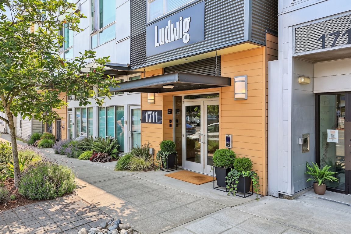 Secure main entrance at Ludwig Apartments in Seattle, featuring contemporary exterior finishes and landscaped sidewalk entry.