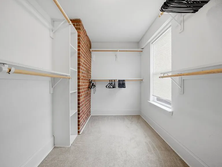 A huge walk-in closet with exposed brick accents.