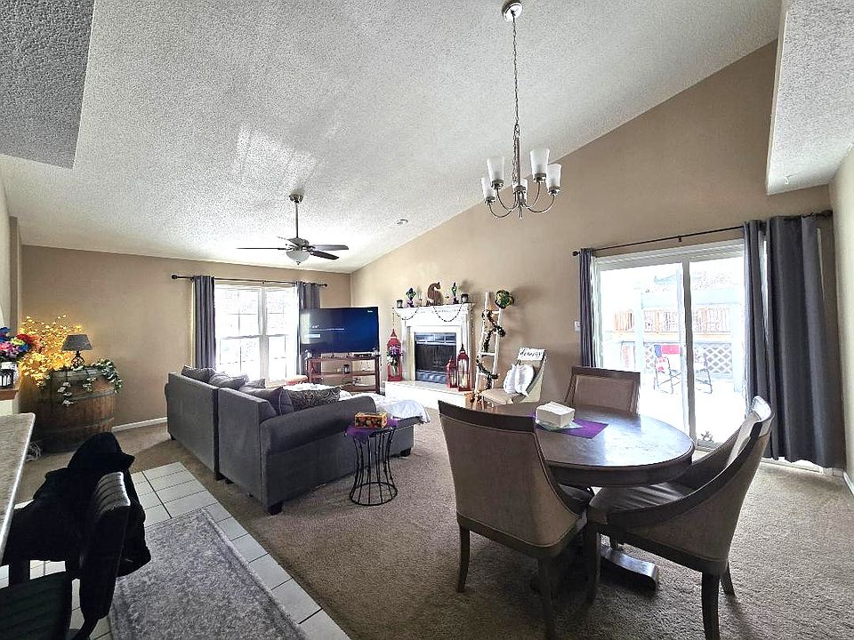 Bright, open living room with vaulted ceilings, large windows, and a cozy gas fireplace.