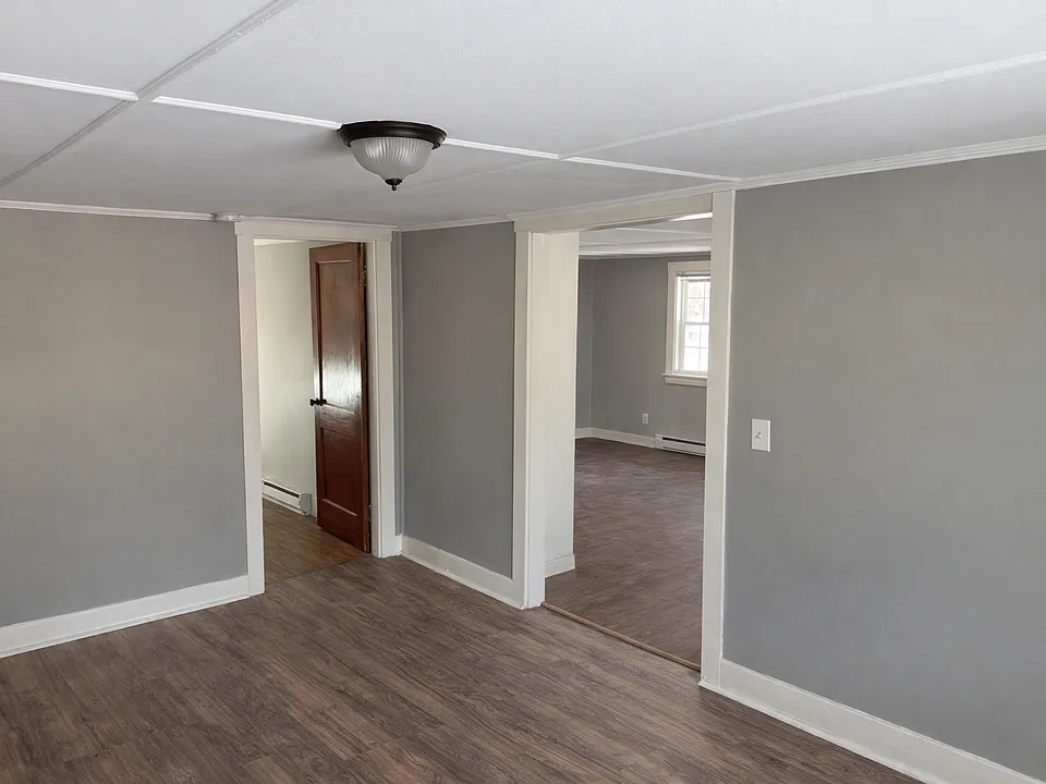 View from living room with bedroom in left rear and to kitchen / exit on the right