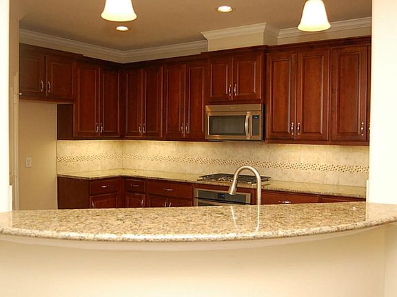 Sample photo- actual finishes may vary. The kitchen overlooks the open dining and living room. This 