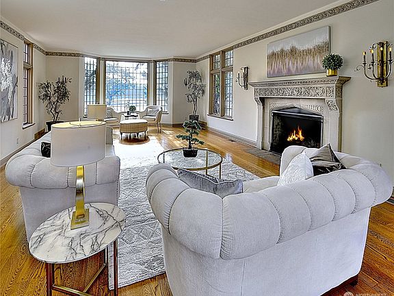 Vast living room with views of Gravelly Lake. Large windows providing an abundance of natural light. Cozy up to considerable size wood fireplace. Enjoy relaxing and reading a book or entertaining in this magnificent space.>