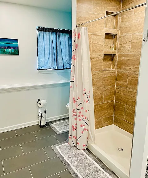 View of shower in master bathroom and hidden toilet area.