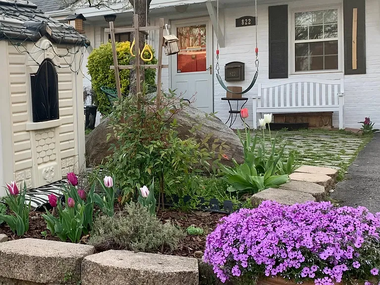 In the front yard there is a herb garden with thyme, mint and lavender next to a playhouse that is painted to match the main house.