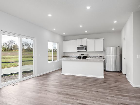 The kitchen has stainless steel appliances and plank flooring.