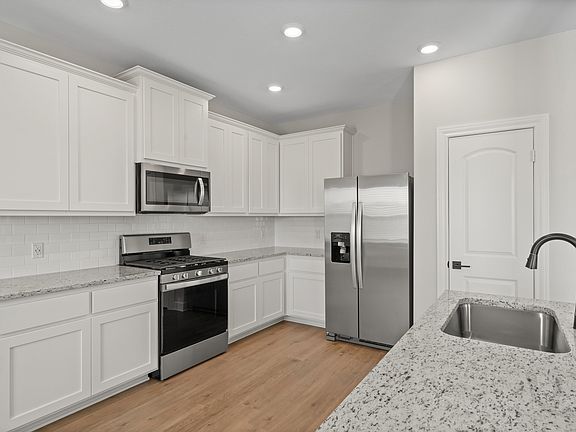 The kitchen has white cabinetry.