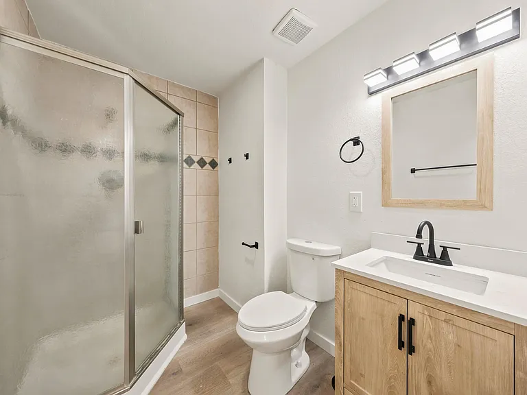 Updated full bathroom with walk-in tiled shower, vanity with storage, and modern lighting for daily convenience.