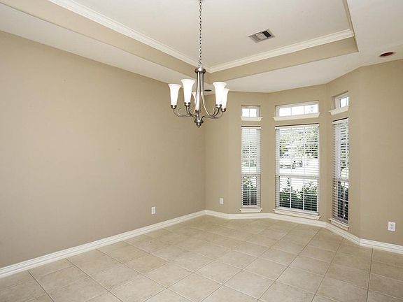 SPACIOUS FORMAL DINING ROOM WITH CEILING DETAILS AND TILE FLOORS.