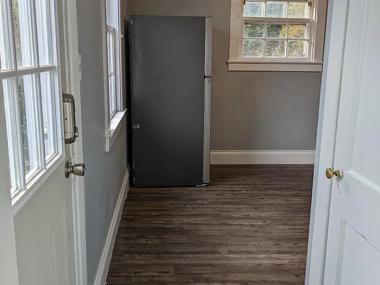 Door to left is side entrance/exit. Door to right is down to the basement. Looking into kitchen standing in living room