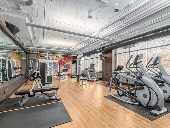 Modern fitness center with state-of-the-art equipment, colorful mural, and ample natural light.