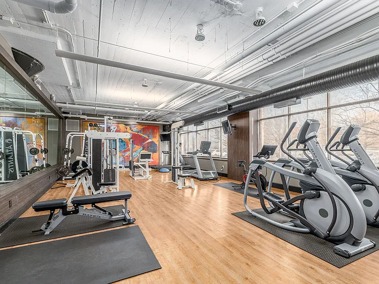 Modern fitness center with state-of-the-art equipment, colorful mural, and ample natural light.