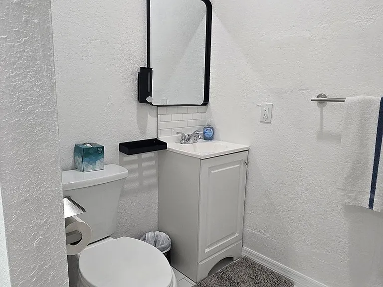 bathroom with pedestal-style vanity,framed mirror, and tile flooringideal for convenient guest use, private bath.