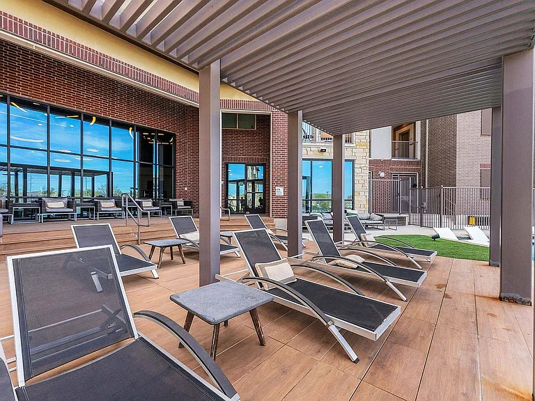 Relax in the shaded outdoor lounge by the pool at Discovery Park Apartments in Denton.