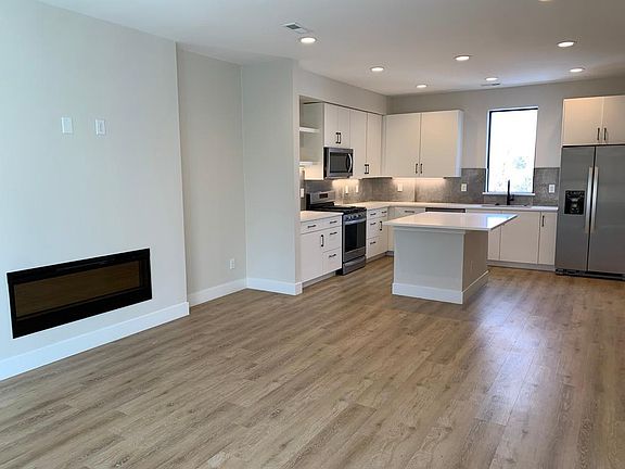 Living room with fireplace and kitchen with stainless steel appliances.