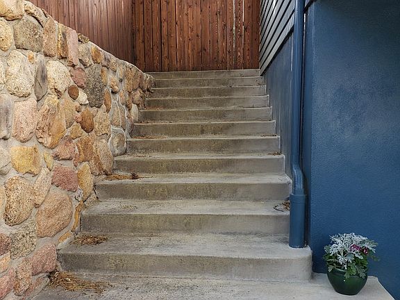 Stairs to side of house lead up to top floor entrance and into full fenced yard.