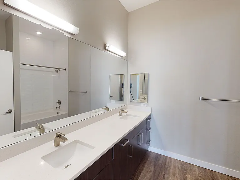 Apartment bathroom with large soaking tub, wood-style flooring and double sinks.