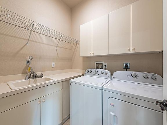 Laundry room with extra fixtures and washer and dryer & plenty of cupboards for storage.