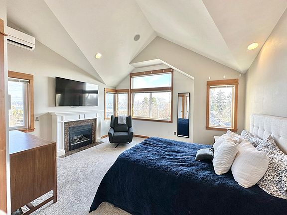 Primary bedroom: Enjoy your primary bedroom with vaulted ceilings, A/C, a gas fireplace and expansive views of the Seattle skyline.