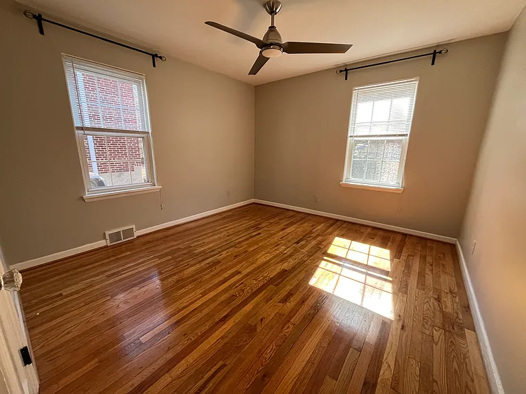 Second bedroom with ceiling fan and curtain rods provided.
