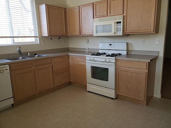 Huge kitchen with breakfast bar behind the photographer. Stainless side by side refrigerator with ice maker and filtered water. Double sink, dishwasher, stove, oven and mircrowave.