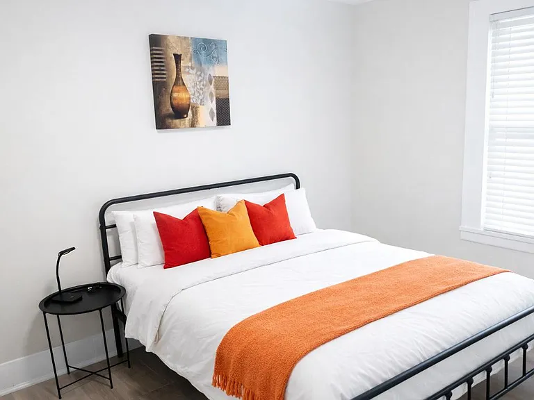 Comfortable bedroom with a full-size bed, nightstand, and window blinds for light control and privacy.