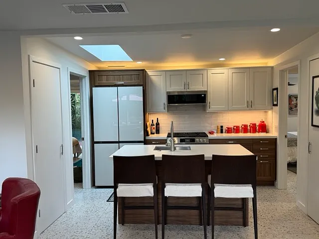 Kitchen and breakfast bar. Direct view with doors to bedrooms at left and right. Full walk-in pantry to left, and washer dryer to right.