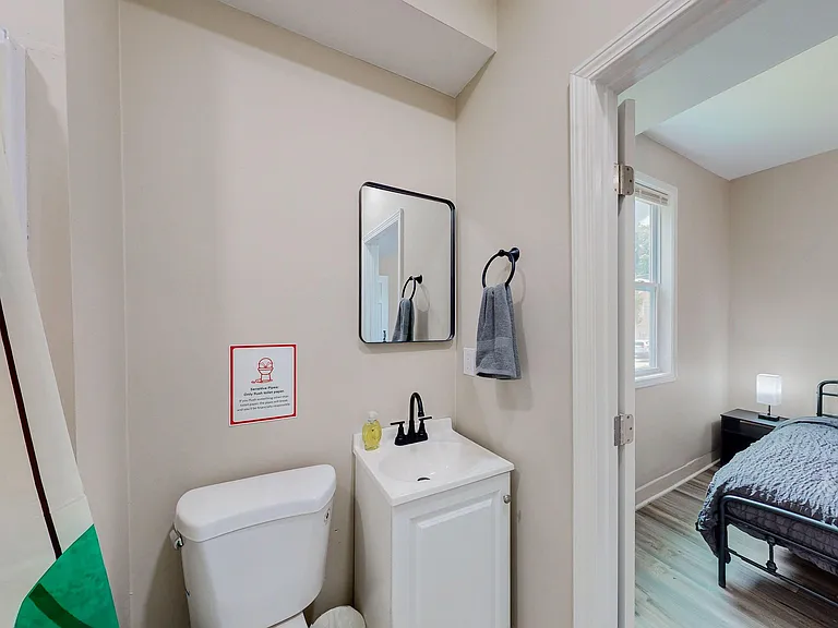 Well-appointed bathroom with a vanity sink, wall mirror, and convenient towel ring just off the bedroom hallway.