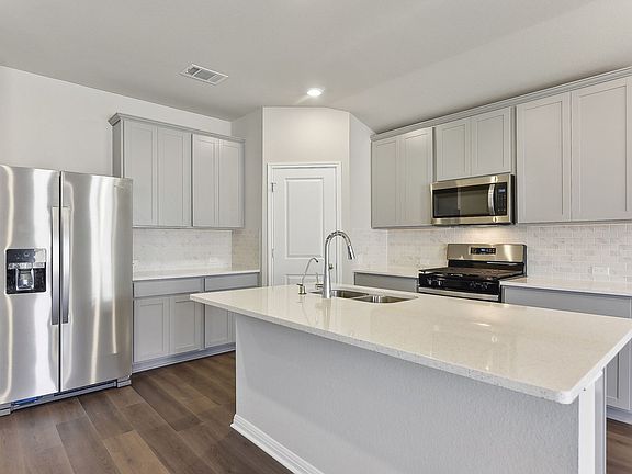 This beautiful kitchen features stone colored cabinets and quartz countertops.