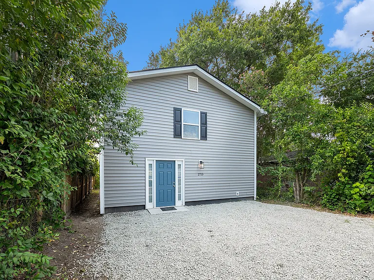 Front of home with gravel parking area for multiple vehicles