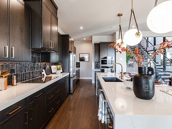 A modern and stylish kitchen with dark cabinets, a white countertop, and decorative elements such as