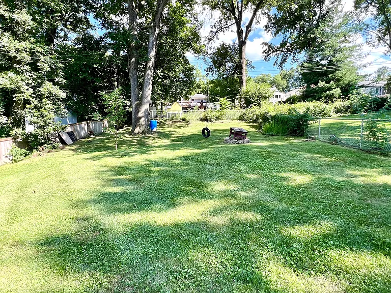 Large, gently sloping backyard with low hung tire swing and fire pit. Mowing and trimming included with rent.