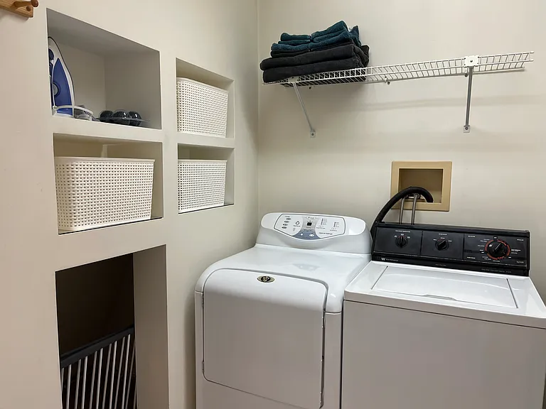 Separate in unit laundry room has washer dryer, iron and ironing board, drying rack and storage.