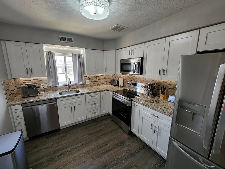 Fully renovated kitchen with white shaker cabinets, granite countertops, stainless steel appliances
