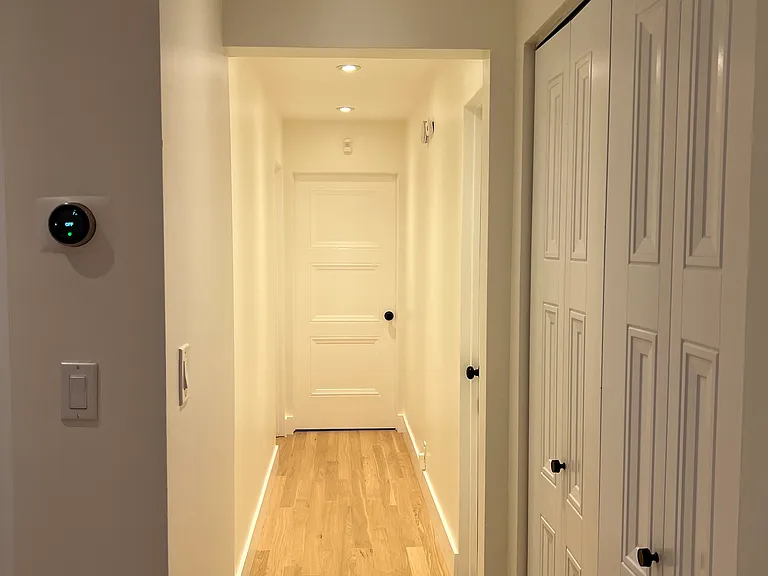 Hallway facing primary bedroom. Other two bedroom doors on either side.