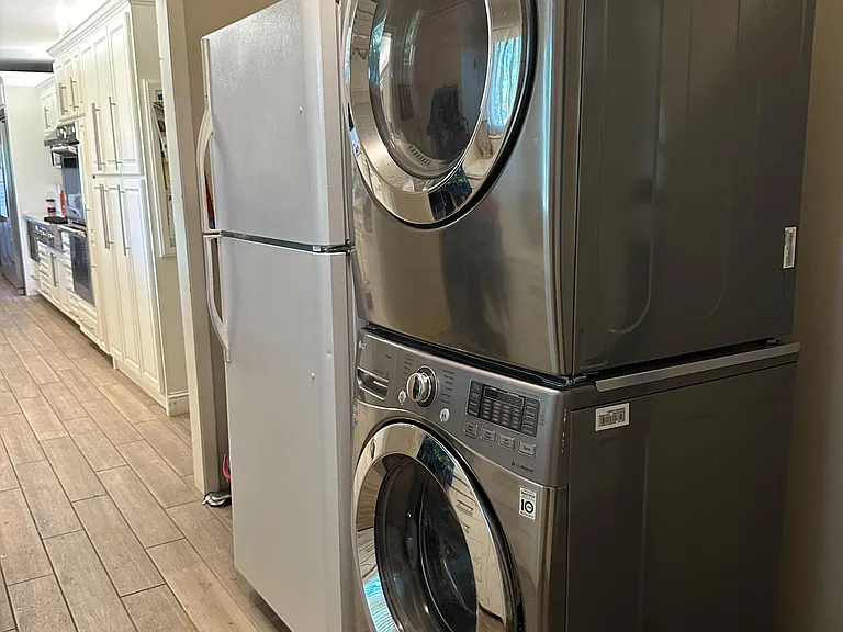 Convenient laundry area with a full-size stacked washer and dryer, located just off the kitchen for easy daily use.