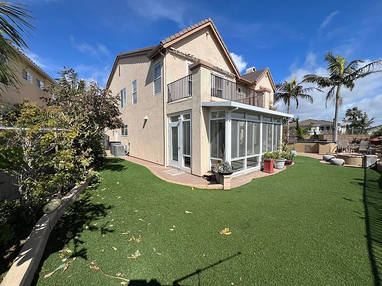 Backyard with artificial turf/grass. View of the sunroom from outside.
