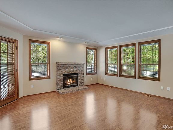 The living room is warmed by a wood-burning fireplace. A side door provides access to the wrap-around deck. 