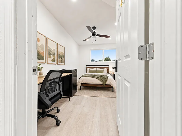 Bedroom with a full bed, desk workspace, ceiling fan, and large window for natural light.
