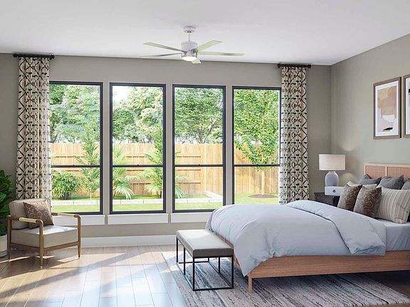 A cozy and well-furnished bedroom with large windows overlooking a lush, green outdoor space.