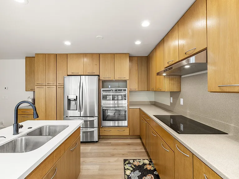 Spacious kitchen with ample wood cabinetry, long countertops, double sink, and stainless steel appliances for easy meal prep.