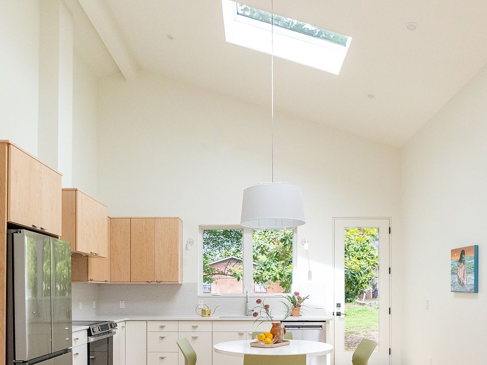 Large Eat-in kitchen with vaulted ceilings, skylights and large windows looking out at back deck.