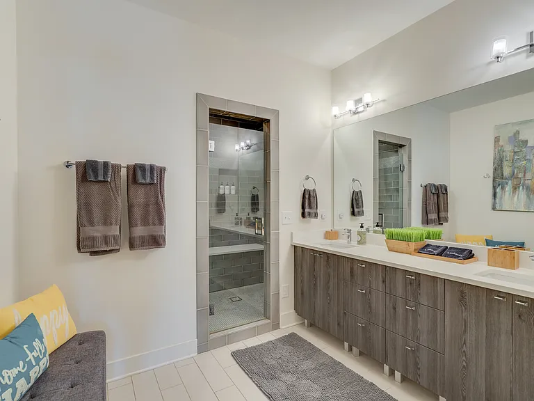 Beautiful primary ensuite bathroom featuring a double-sink vanity, spacious walk-in rainfall shower, private water closet, and additional seating, creating a spa-like retreat to relax and refresh.