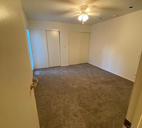 Spacious master bedroom with door to yard & ceiling fan.