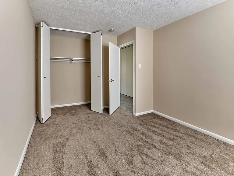 Comfortable bedroom with wall-to-wall carpet and generous closet space at Audubon Arms Apartments